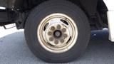 A close-up of a 2011 Ford Econoline tire with a silver wheel featuring multiple bolts and a worn black tire surface