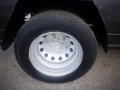 Close-up of a silver steel wheel with multiple holes mounted on a black tire showcasing the tread pattern