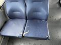 Two worn blue seats with visible tears and scratches showing signs of damage and wear