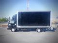 A black 2013 Mitsubishi Fuso FE 160 truck with a large box trailer and dual rear wheels parked on a paved surface