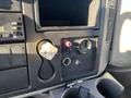 The interior dashboard controls of a 2013 International 4300 featuring a key slot a red battery switch a gauge and a cup holder