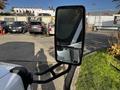 A 2015 Chevrolet Express side mirror reflecting part of the vehicle with a clear view of the glass and mounting arm