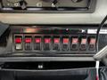 A dashboard panel featuring multiple toggle switches in red and black for various functions on a 1994 Freightliner FL80 truck