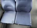 A pair of worn and torn blue fabric seats from a 2017 Chevrolet Express showing signs of usage and damage