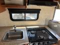 A 2012 Ford Econoline van interior featuring a kitchen area with a sink and a stove