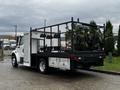 A 2005 Freightliner M2 106 with a flatbed and various attachments mounted on the rear including rows of tools or equipment holders