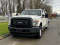 A white 2014 Ford F-250 Super Duty pickup truck with a black grille and utility bed parked on a street