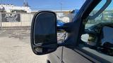 A black 2013 Ford Econoline van's side mirror is prominently featured in the foreground