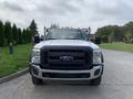 A 2012 Ford F-550 in white with a black grill and multiple orange lights on the roof facing directly towards the viewer