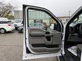 A 2018 Ford F-150 with an open driver's side door showcasing the interior door panel and controls