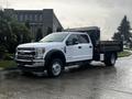 A 2021 Ford F-550 white pickup truck with a flatbed attachment parked on a wet surface