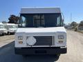 A white 2011 Ford Econoline van with a large front grill and multiple windows in a straight-on view