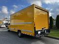 A 2017 GMC Savana box truck with a bright yellow exterior parked at an angle showing its rear and side features including rolling doors and a flat rear bumper