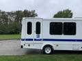 A white 2015 Chevrolet Express with a blue stripe and a wheelchair accessibility symbol on the side