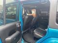 Interior view of a blue 2020 Jeep Wrangler showing front and back seats with black upholstery and a visible center console