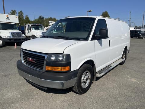 A white 2016 GMC Savana van with a black front grille and large headlights parked on a paved surface