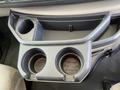 Cupholder area of a 2012 Ford Econoline featuring two round spaces for cups and a smaller compartment on the side