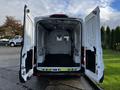 Open rear doors of a 2020 Ford Transit van revealing a spacious cargo area with a flat floor and a partition at the back