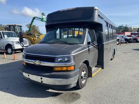 A 2017 Chevrolet Express bus with a dark gray exterior and a distinctive front grille is parked at an angle with visible step-up entry and large windows