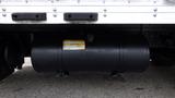 A black fuel tank with a yellow label mounted underneath a 2016 Hino 195 truck