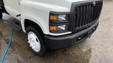 A 2021 International CV515 truck with a white body and black grille displays its front headlights and wheel with visible water droplets