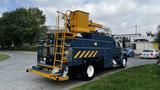 A blue 2009 International 4300 truck with a yellow bucket lift attached at the rear and safety markings on the sides