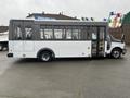 A 2018 Chevrolet Express bus with a white exterior and large windows parked on a flat surface