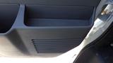 Interior door panel of a 2012 GMC Savana featuring a storage compartment and ventilation grooves