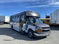 A 2017 Chevrolet Express bus with a gray front and white body parked with the doors open