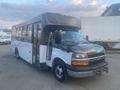 A 2017 Chevrolet Express bus with a black front and white body parked with its door open