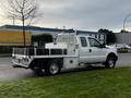 A 2014 Ford F-250 SD with a flatbed and toolboxes parked on the side of the road