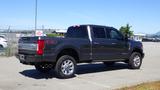 A 2017 Ford F-350 SD in dark gray with chrome accents and dual exhaust pipes parked at a lot