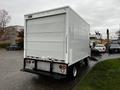 A white 2012 Mitsubishi Fuso FE box truck facing away with a plain rear and rolling door