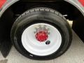 Close-up of a Michelin tire mounted on a red and white wheel rim with visible lug nuts and a red hub in the center