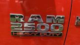 Close-up of a shiny chrome emblem displaying the text RAM 2500 HEAVY DUTY on a red vehicle