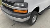 A 2017 Chevrolet Express Quigley 4x4 with a silver and white exterior featuring a distinctive front grille and a prominent Chevrolet logo on the hood