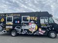 2011 Ford Utilimaster Food Truck with a black exterior featuring colorful graphics of food items and text promoting catering and fried chicken