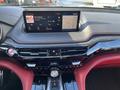 The dashboard of a 2023 Acura MDX featuring a touchscreen display with radio information and climate controls in a sleek black and red interior design