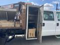 A 2010 Ford F-550 with an open compartment showing a cardboard box inside and several hooks mounted on the interior wall