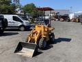 A yellow 2024 Traner TR 45 loader with a front bucket and protective canopy positioned on an industrial lot