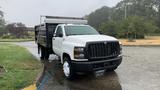 A 2021 International CV515 truck with a white cab and a black dump bed parked on a wet surface