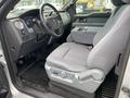 Interior view of a 2013 Ford F-150 showing the driver's seat steering wheel and dashboard with controls and a grey cloth seat