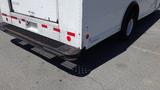 A 2011 Ford Econoline rear view showing a rusted bumper and a perforated step with red and white reflective strips