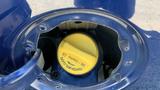 Close-up of a fuel cap in a 2013 Ford Econoline with a yellow twist-off cap labeled for fuel type and instructions