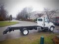 2006 International 4300 flatbed truck with a white cab and black chassis parked on a street