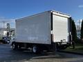 A white 2020 Isuzu NPR box truck is parked with its rear facing the viewer showcasing a clean and smooth surface on the truck's cargo area