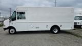 A white 2006 Ford Econoline cargo van with a boxy shape and one side door parked on gravel