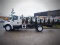 A white 2006 International 4300 truck with a flatbed chassis parked on a concrete surface