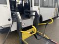 A yellow wheelchair ramp extended from a bus entrance with a black metal frame and safety straps visible