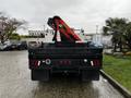 A 2014 Ford F-550 flatbed truck is parked with a red crane attachment visible on the back and lights and reflective features on the rear side